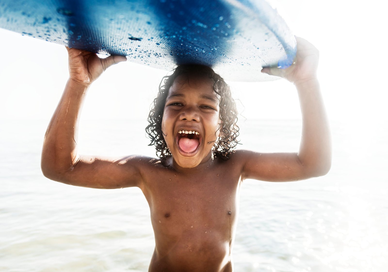 a little boy carrying a surfboard